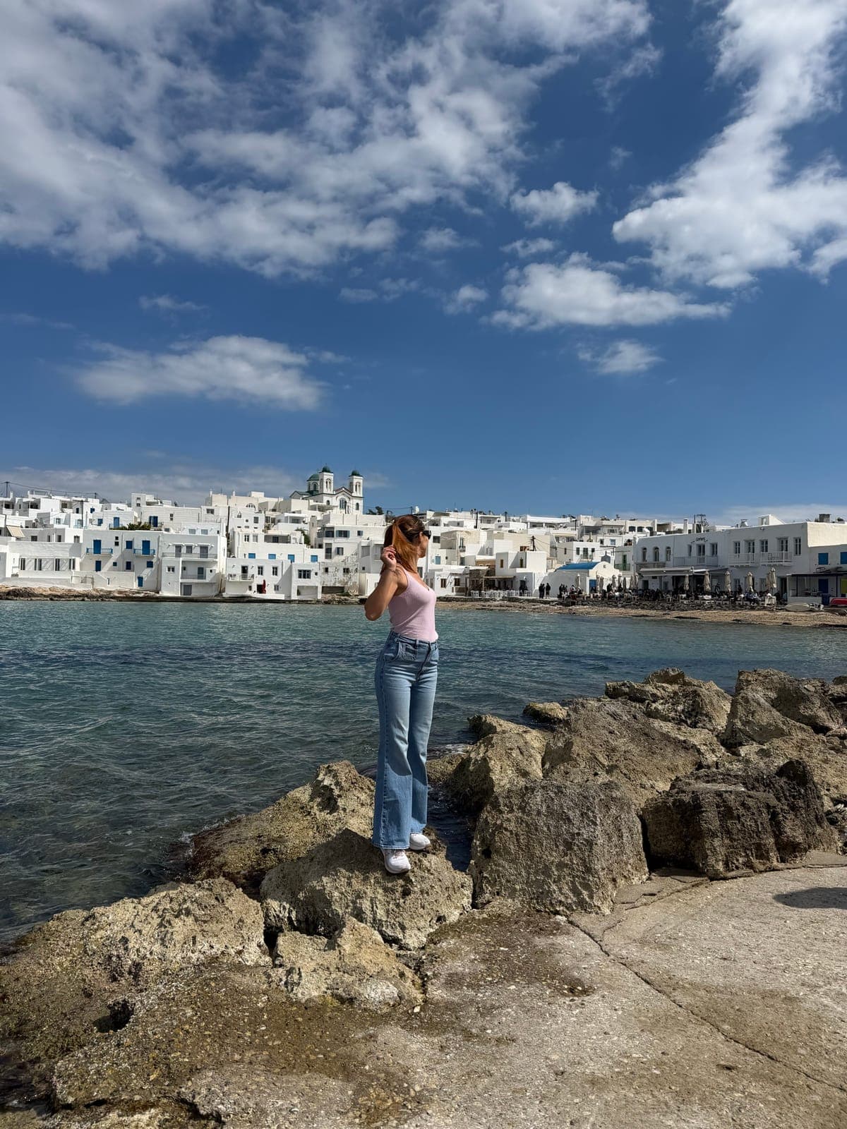 Katarina by the sea in front of a Cycladic harbor village