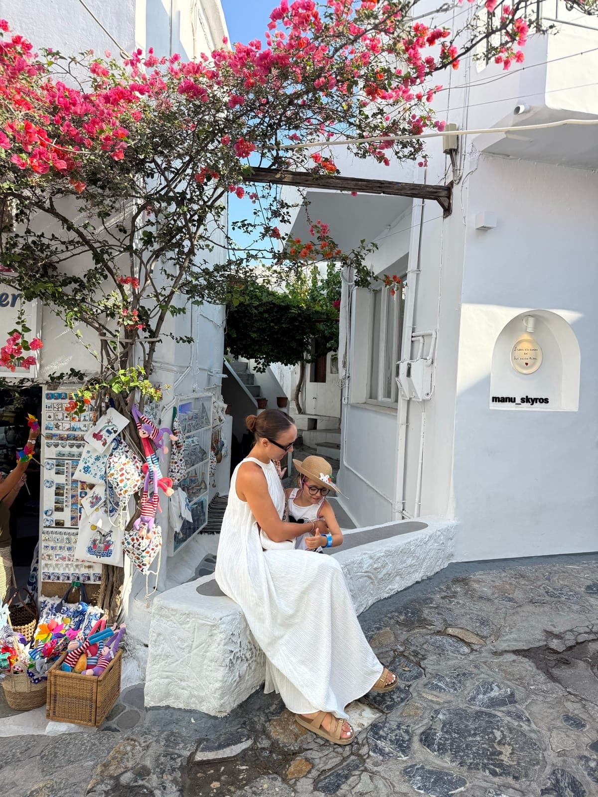Katarina with her daughter on a whitewashed street in Santorini